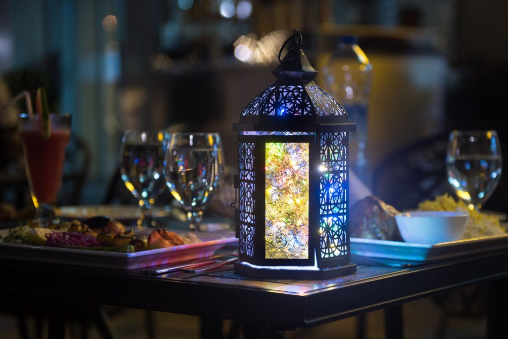 فانوس رمضاني مضاء على طاولة طعام في مطعم عربي بمونتريال، يبرز الأجواء الشرقية المميزة خلال المناسبات الخاصة.