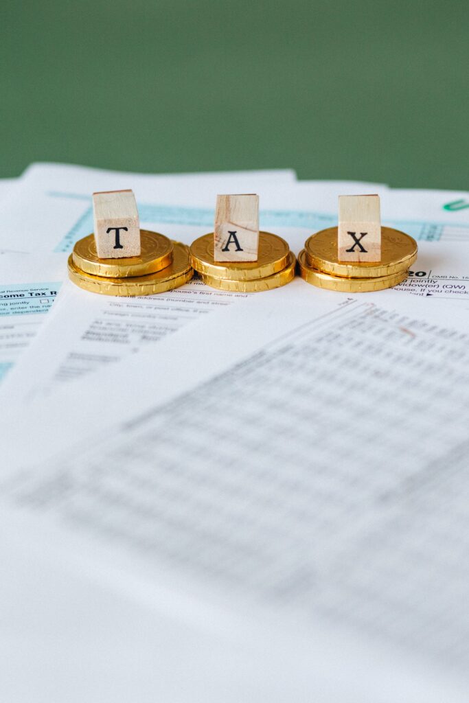 مجموعة من الأوراق الضريبية فوقهل قطع من النقود موضوع عليها مكعبات تحمل اسم TAX