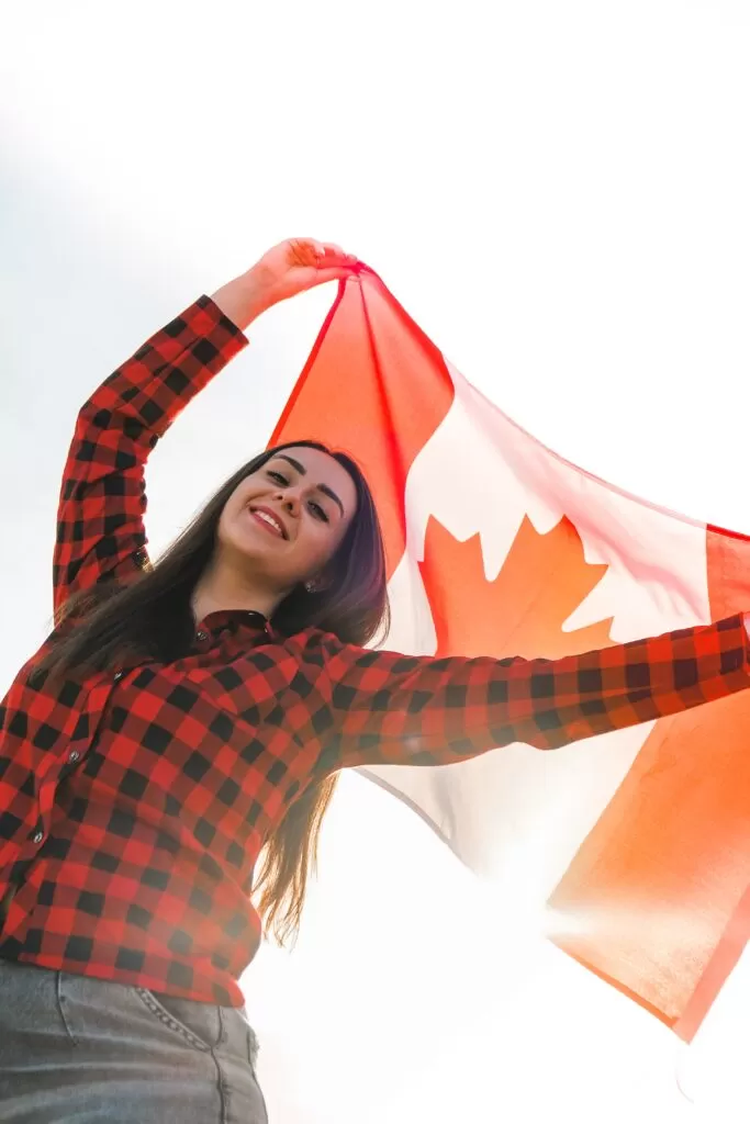 بنت تحمل العلم الكندي في الهواء خلف رأسها فخر الجنسية الكندية
