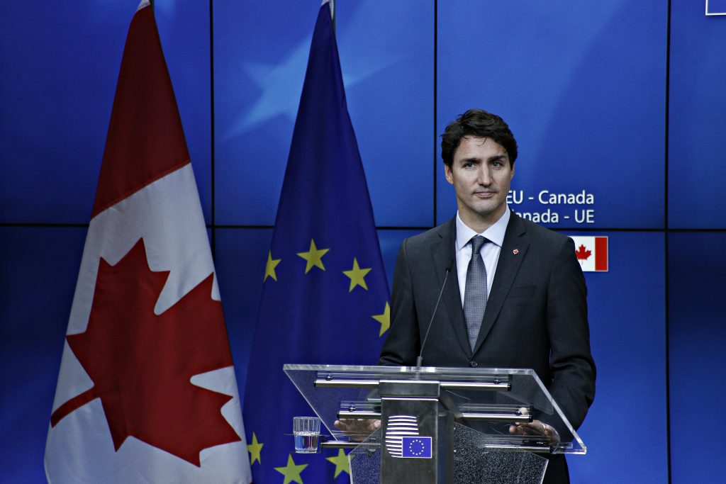 جاستن ترودو يقف على منصة مع أعلام كندا والاتحاد الأوروبي في الخلفية.