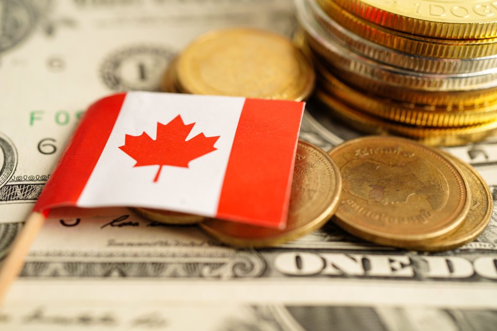 علم كندا مصغر موضوع على خلفية من العملات المعدنية وأوراق نقدية مختلفة من بنوك كندا.
