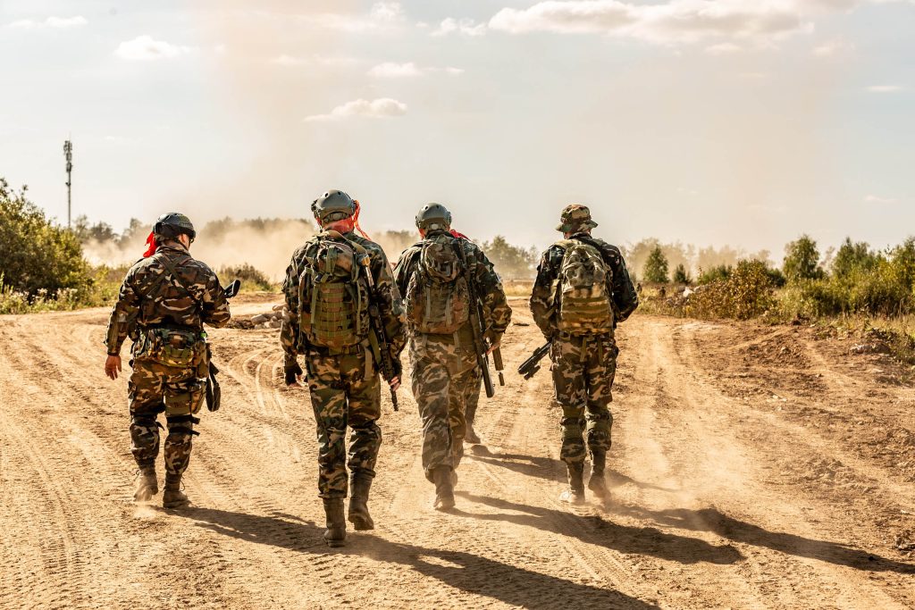 أربعة جنود يرتدون ملابس مموهة ويسيرون على طريق ترابي.
