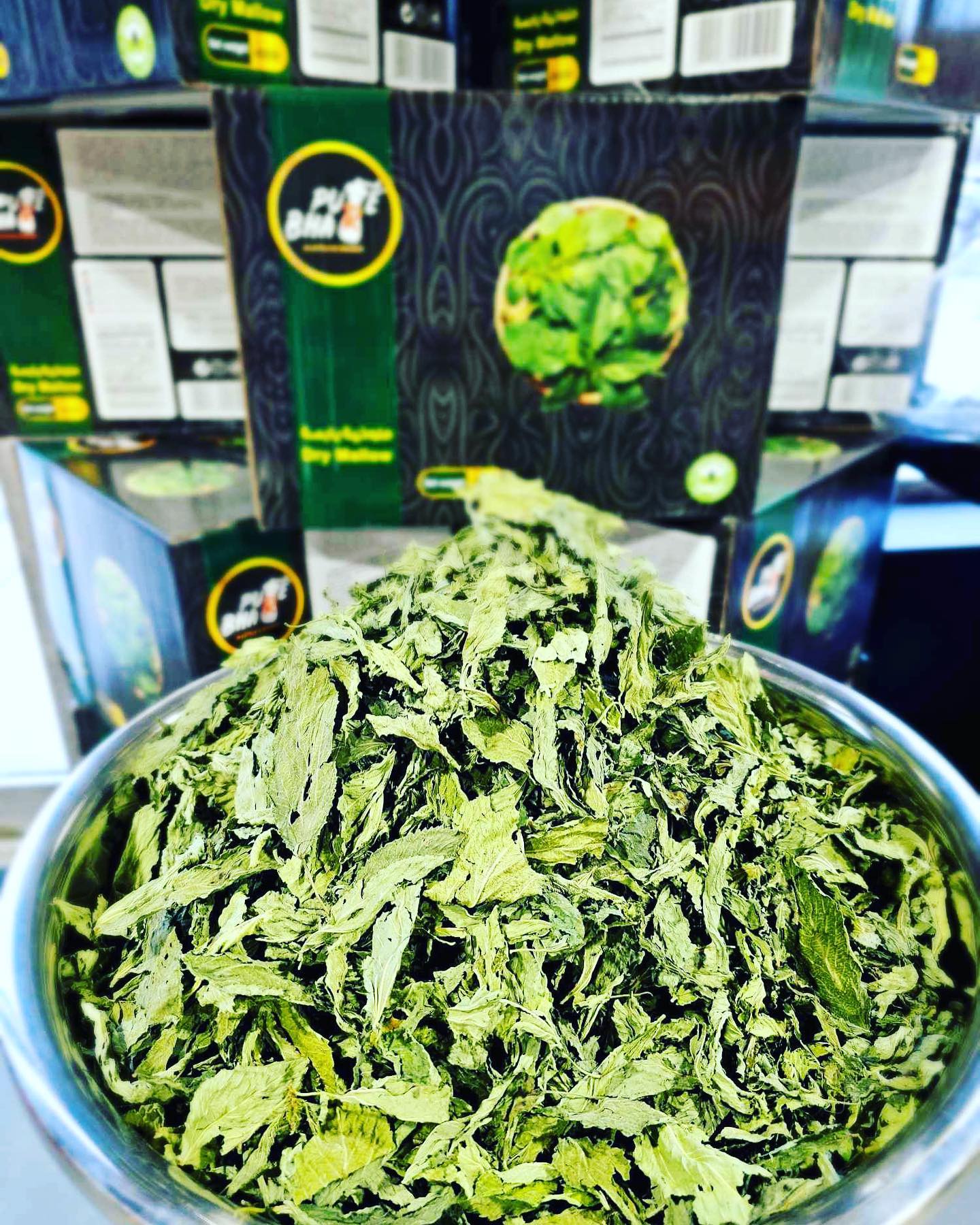 A bowl filled with dried leaves is placed in front of several of the same product.