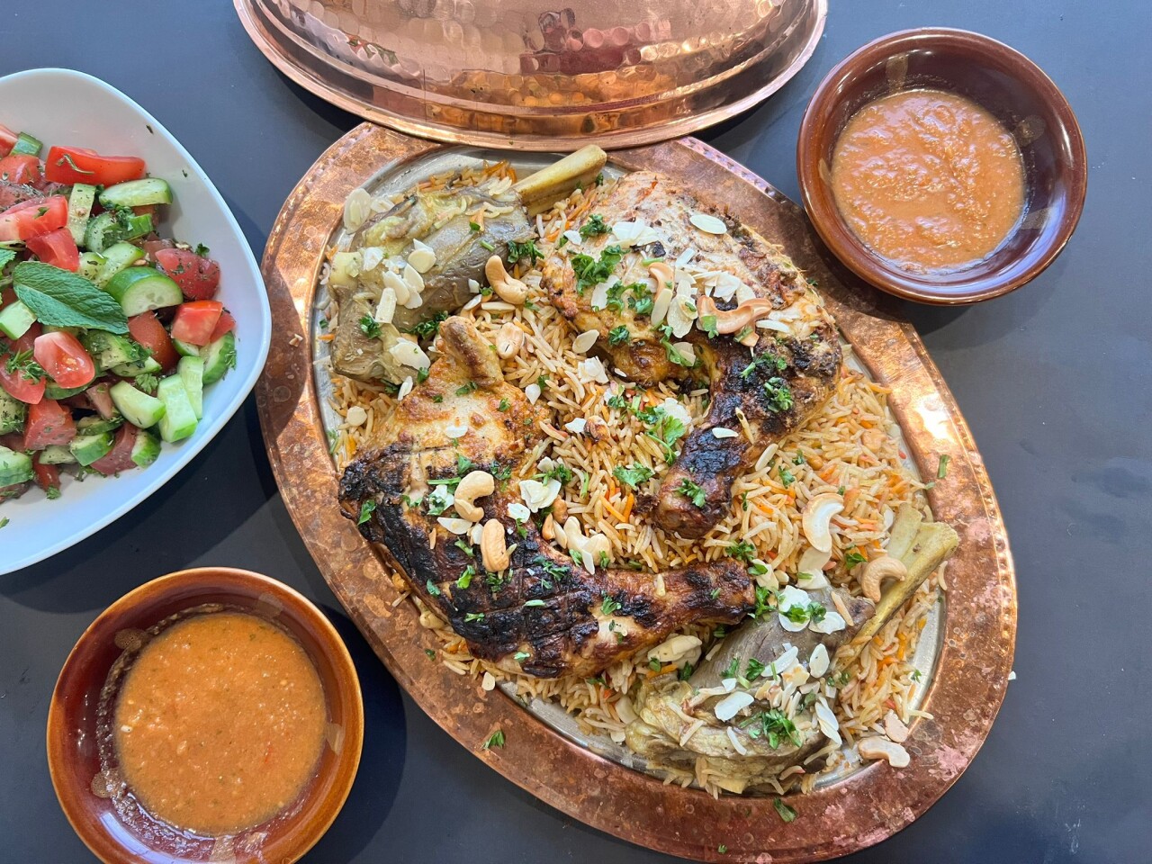 Grilled meat platter with yellow rice, fresh salad and sauce bowl on the side.