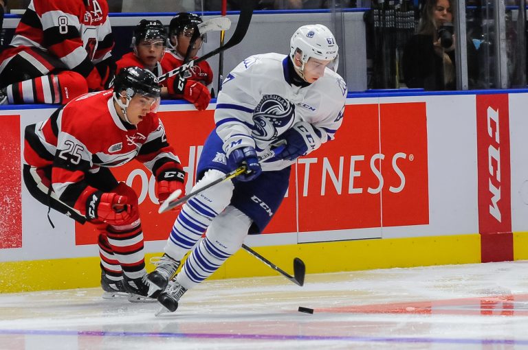 الرياضة في كندا - Two -players -chasing- a -hockey- puck -on a- white- floor