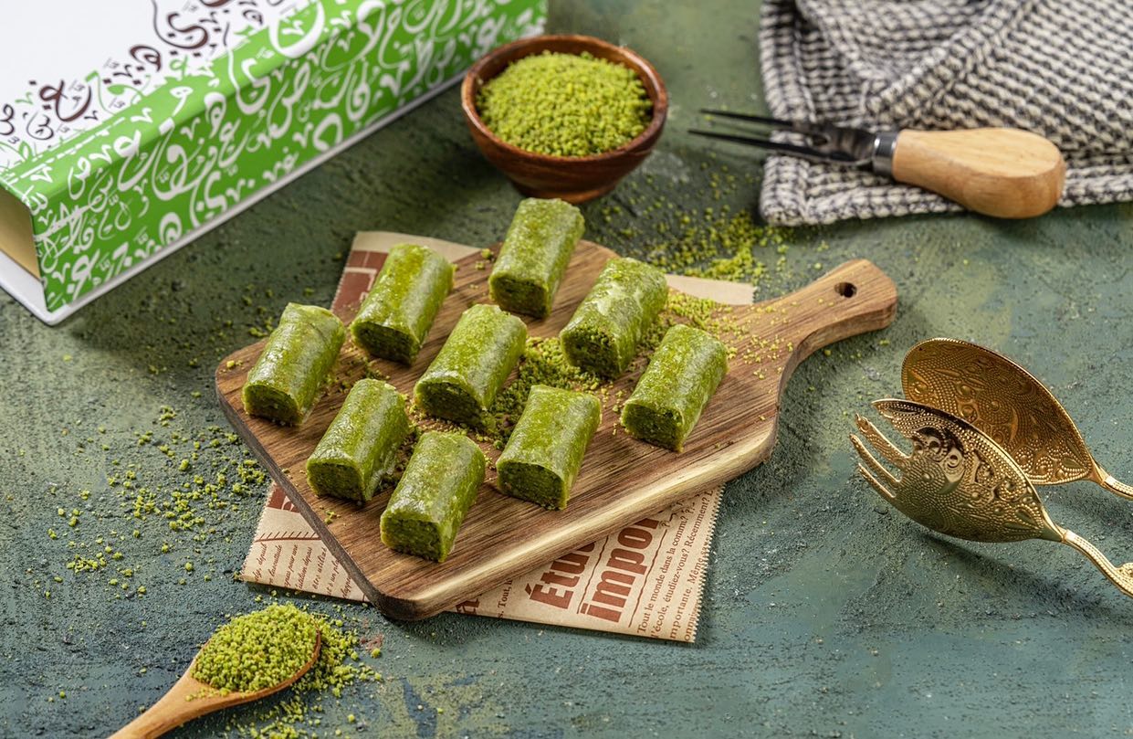 A wooden board containing several pieces of pistachio baklava, arranged elegantly.