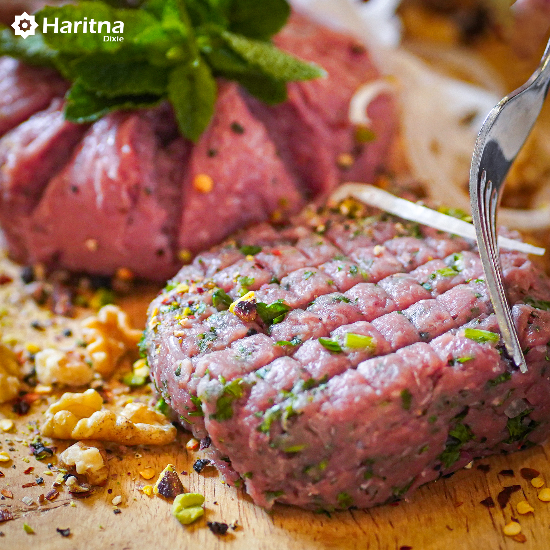 A piece of raw meat garnished with herbs with a fork inserted into the meat