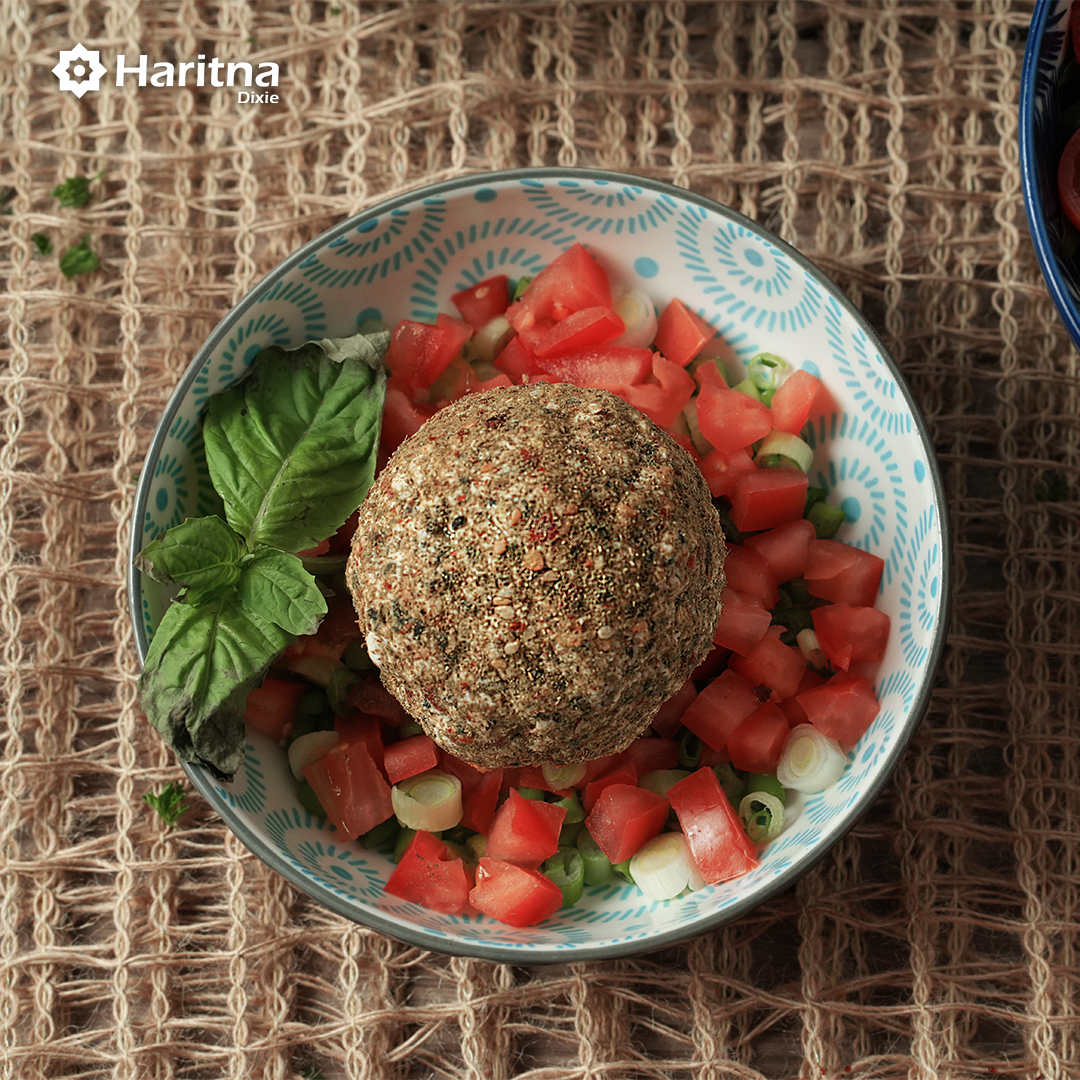 A decorative bowl containing shanklish with tomato cubes, green onions and mint.