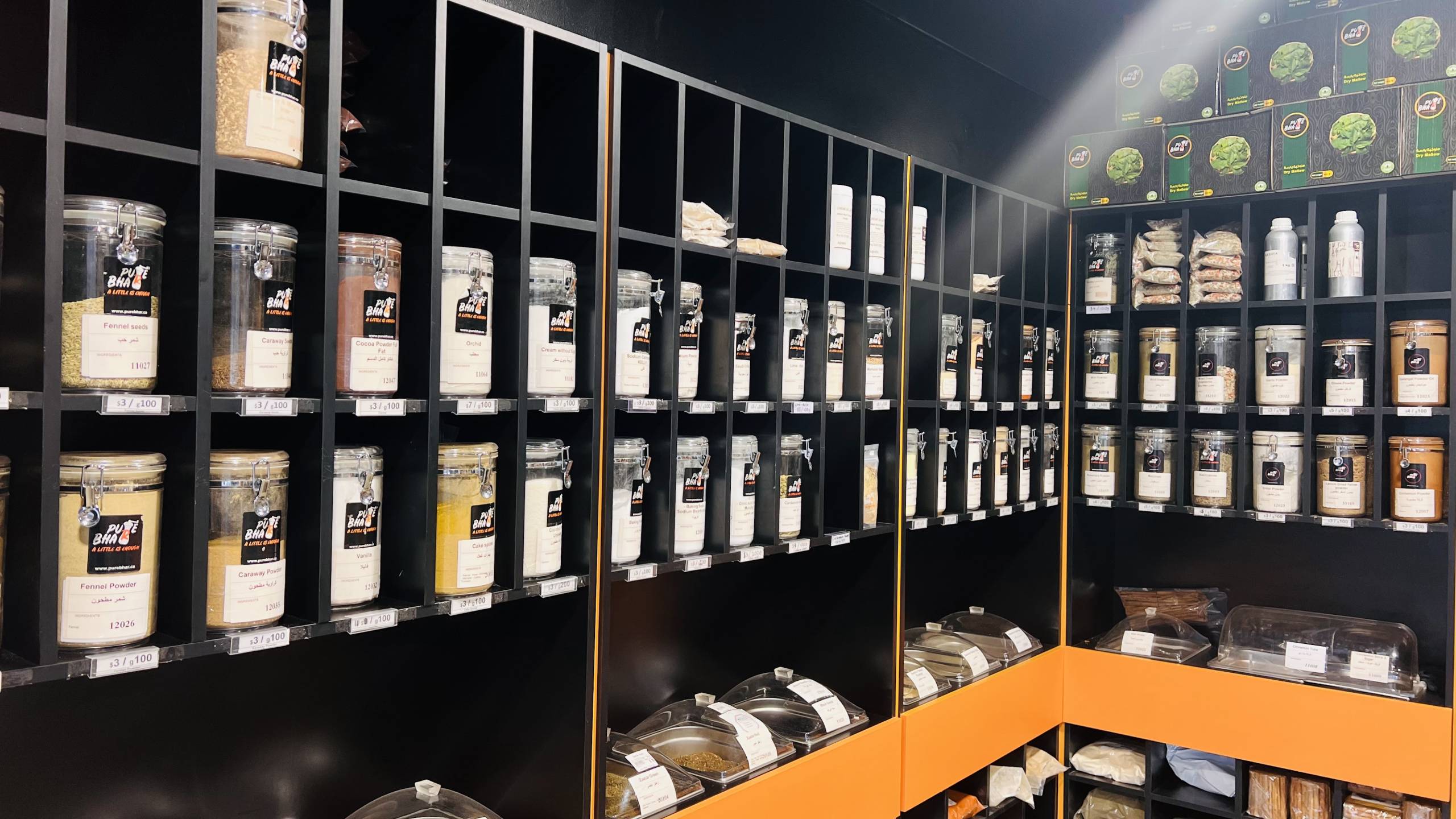 Shelves containing a variety of spices and seasonings in neatly arranged glass jars.
