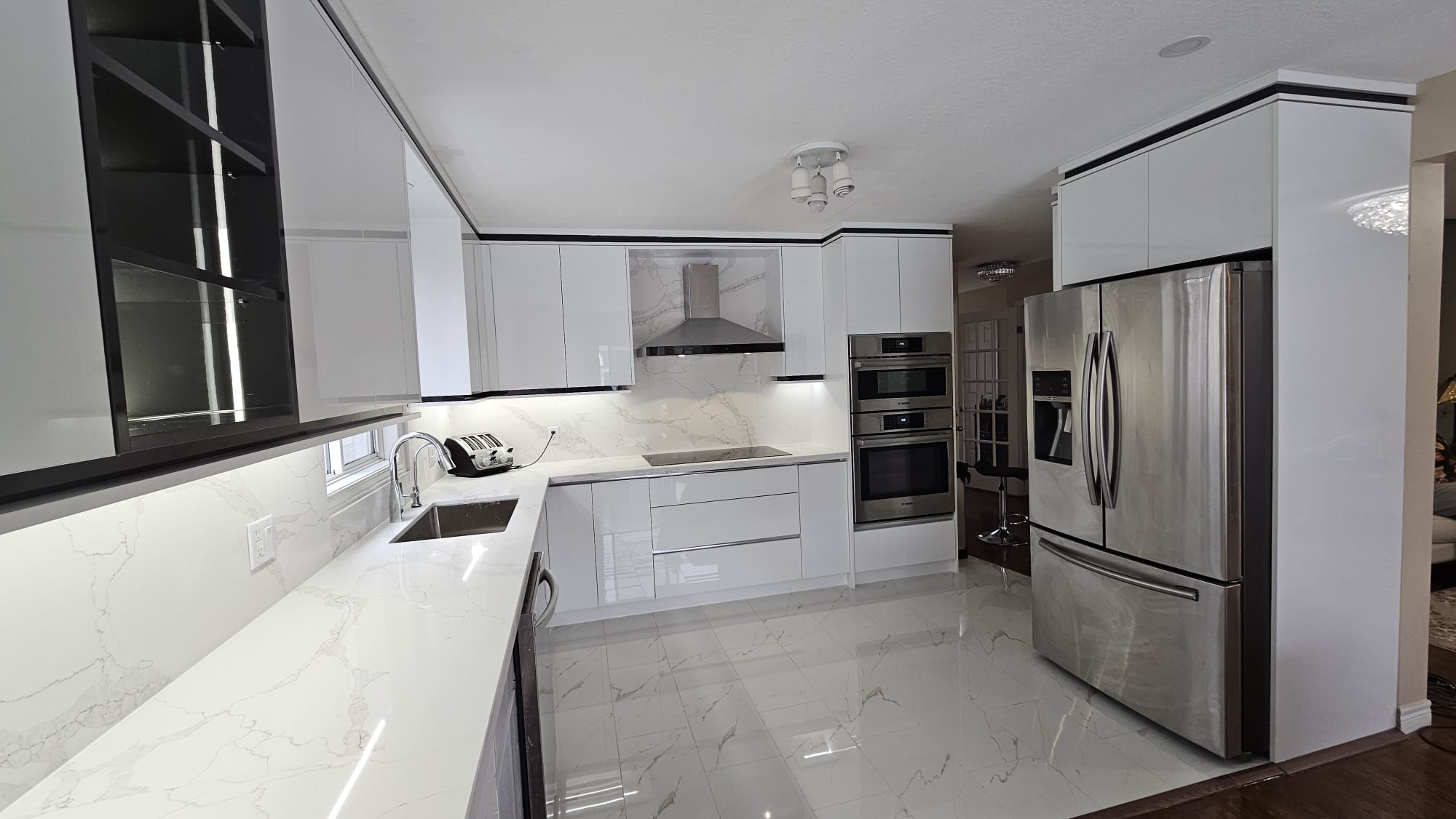 Modern and contemporary kitchen featuring glossy white cabinets and a beautiful silver refrigerator.
