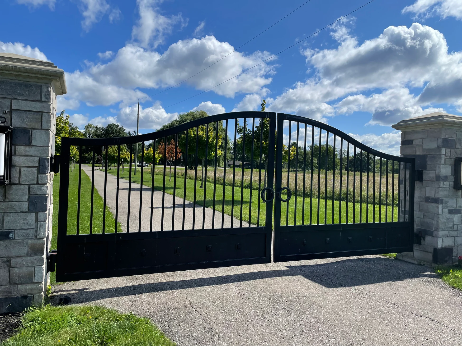 Metals Farm - A closed black metal gate with vertical bars resting between two stone columns.