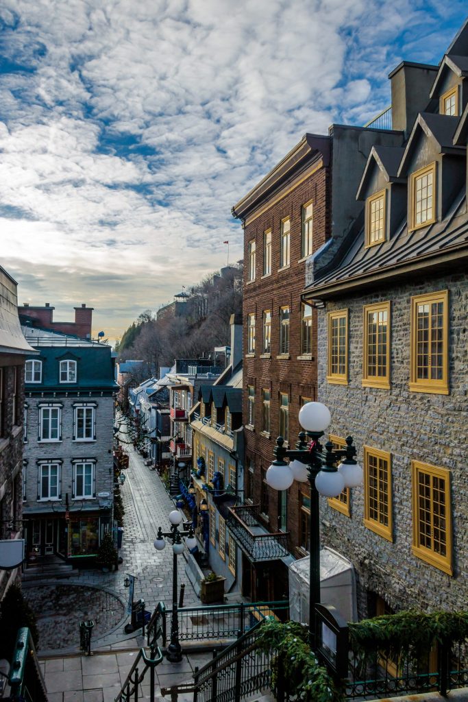 شارع ضيق ومرصوف بالحصى في مدينة كيبيك القديمة، محاط بمبانٍ تاريخية حجرية.