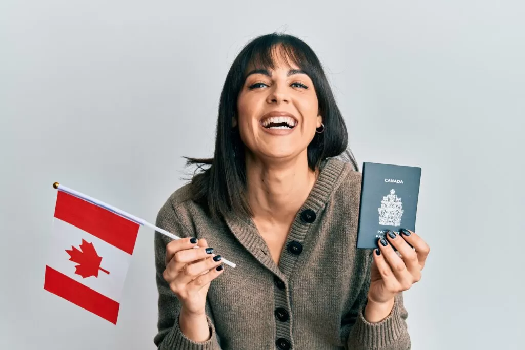 فتاه سعيدة بسبب الهجرة إلى كندا و بيدها جواز سفر كندي و علم كندا